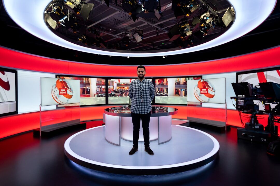 Professional TV news broadcast studio with presenter at anchor desk